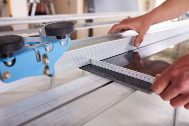 Proceso de fabricación en taller de perfilería de aluminio para ventana con corte de precisión y ensamblaje.